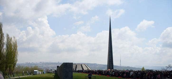 A solemn gathering at a memorial site on Armenian Genocide Memorial Day, with people paying respects and laying flowers in remembrance of the victims.