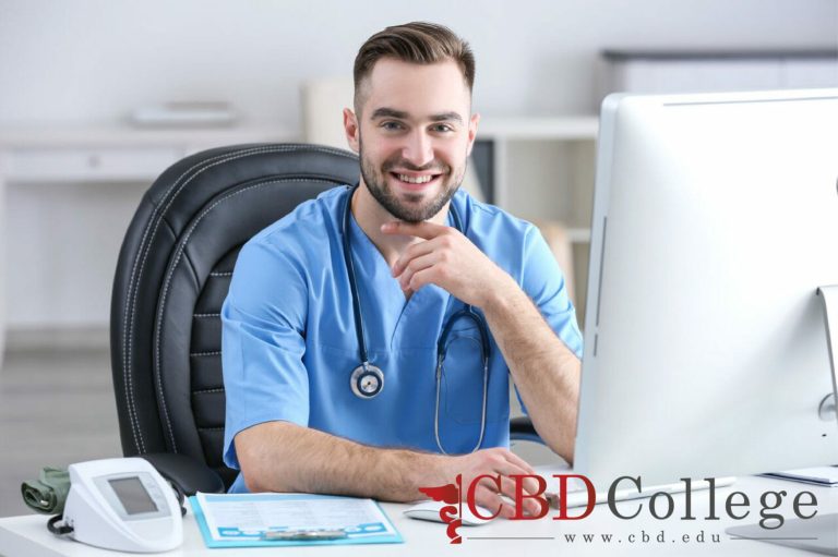 A smiling male medical assistant using a PC.