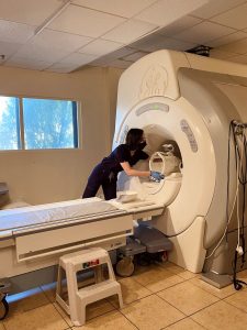 Photograph of Liliane Tran, MRI Program student at CBD College, near an MRI device.