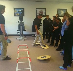 Students and instructors from CBD College's Physical Therapy Assistant program host an Open House event at the Back 2 Health clinic, located on the 5th Floor of CBD College. In the image, students can be seen providing information and demonstrations to attendees, showcasing their expertise in physical therapy practices and techniques.