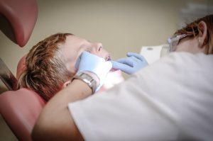 A dental assistant attending to a young boy in a clinic.