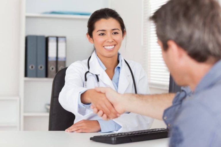 Female doctor shaking hands with a patient in her office.
