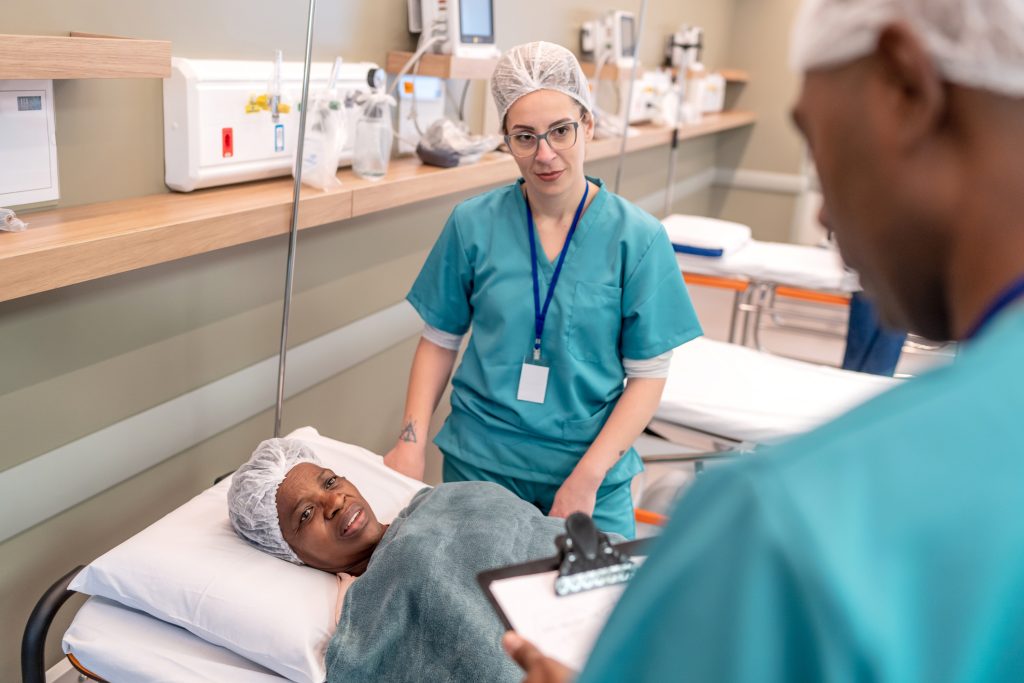 surgical tech with medical assistant talking with patient post surgery